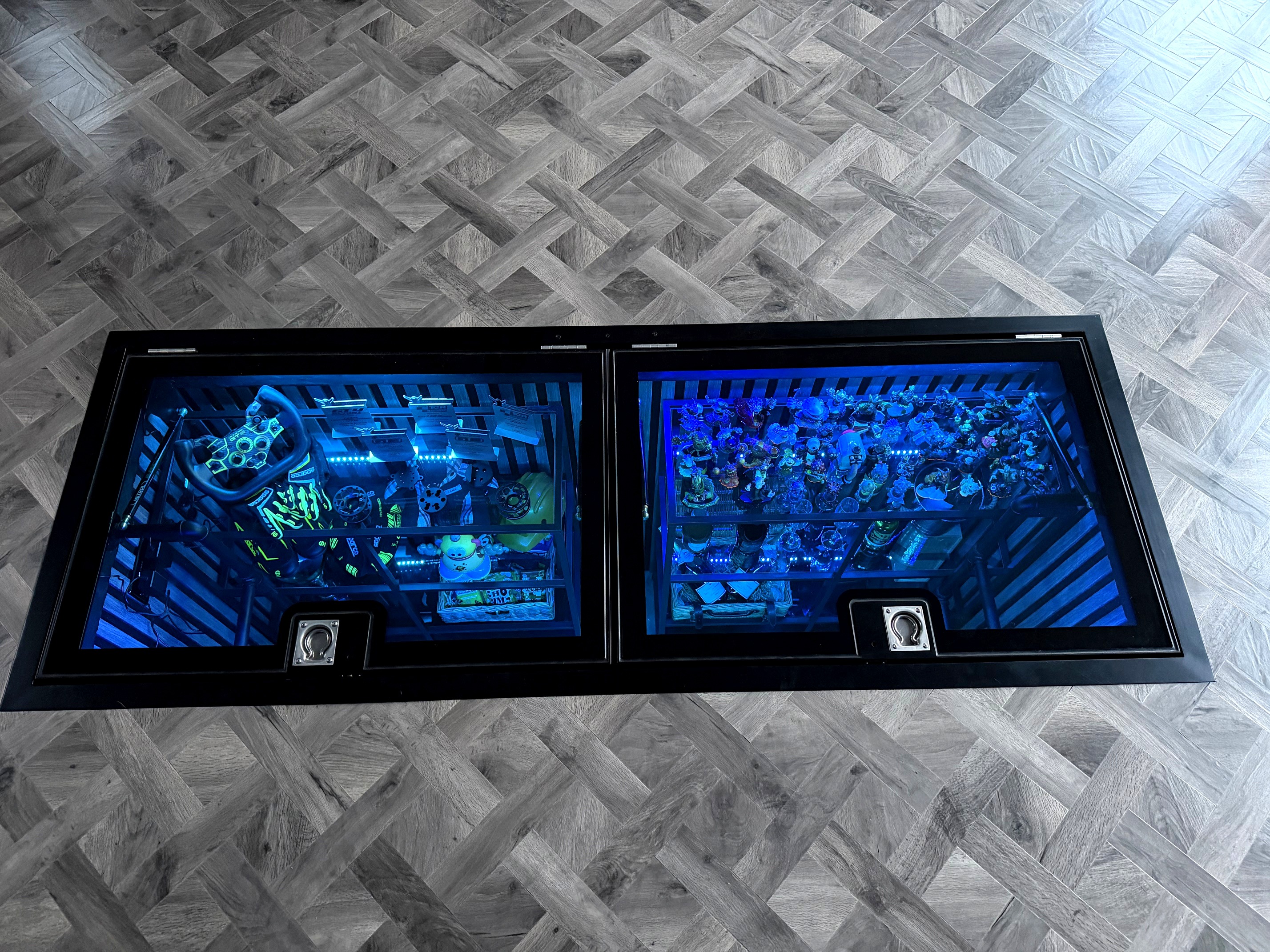 Overhead view of double door hinged glass floor system over garage inspection pit, motorsport memorabilia and champagne display, Ashbourne